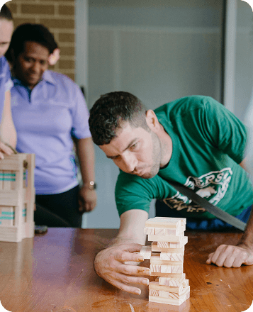 Mark, who is an NDIS patient, is playing Jenga and looks really concentrated in making sure the blocks don't collapse!